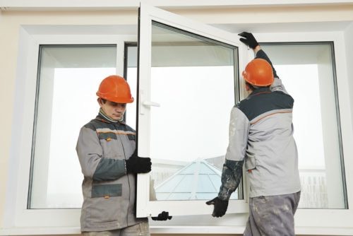 Two male industrial builders workers at window installation