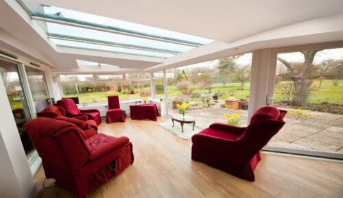 Light-filled conservatory interior with a glazed roof and full-height windows overlooking a garden