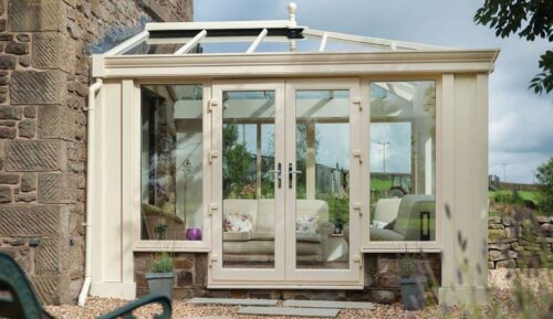 Light-filled conservatory interior with a glazed roof and full-height windows overlooking a garden