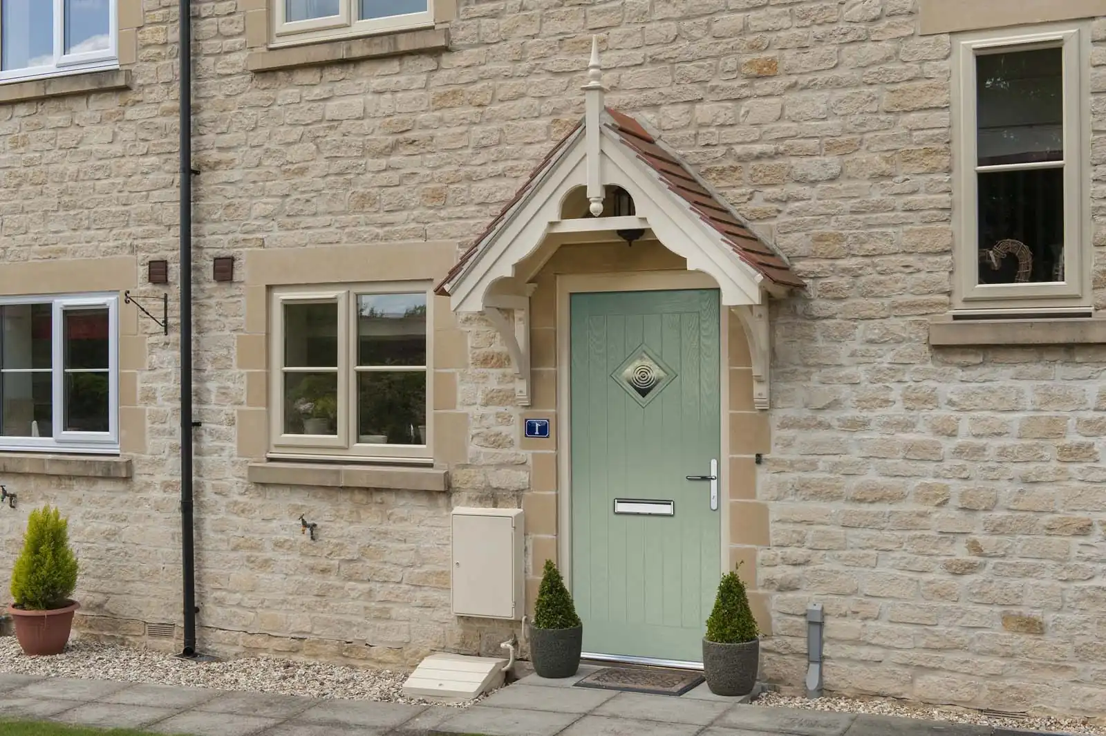 Sage green composite front door with diamond glazing on a Cotswold stone cottage